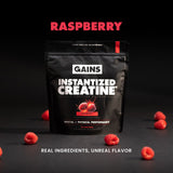 Black package of GAINS Instantized Creatine with sour raspberry flavor on a dark background with raspberries. | sour raspberry