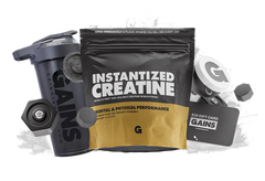 A bag labeled Instantized Creatine Special Offer sits on a gray, textured background with a shaker bottle, two dumbbells, a $20 gift card, and a scoop of creatine powder arranged around it.