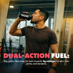 Man drinking from a supplement bottle labeled 'GAINS' in a gym setting.